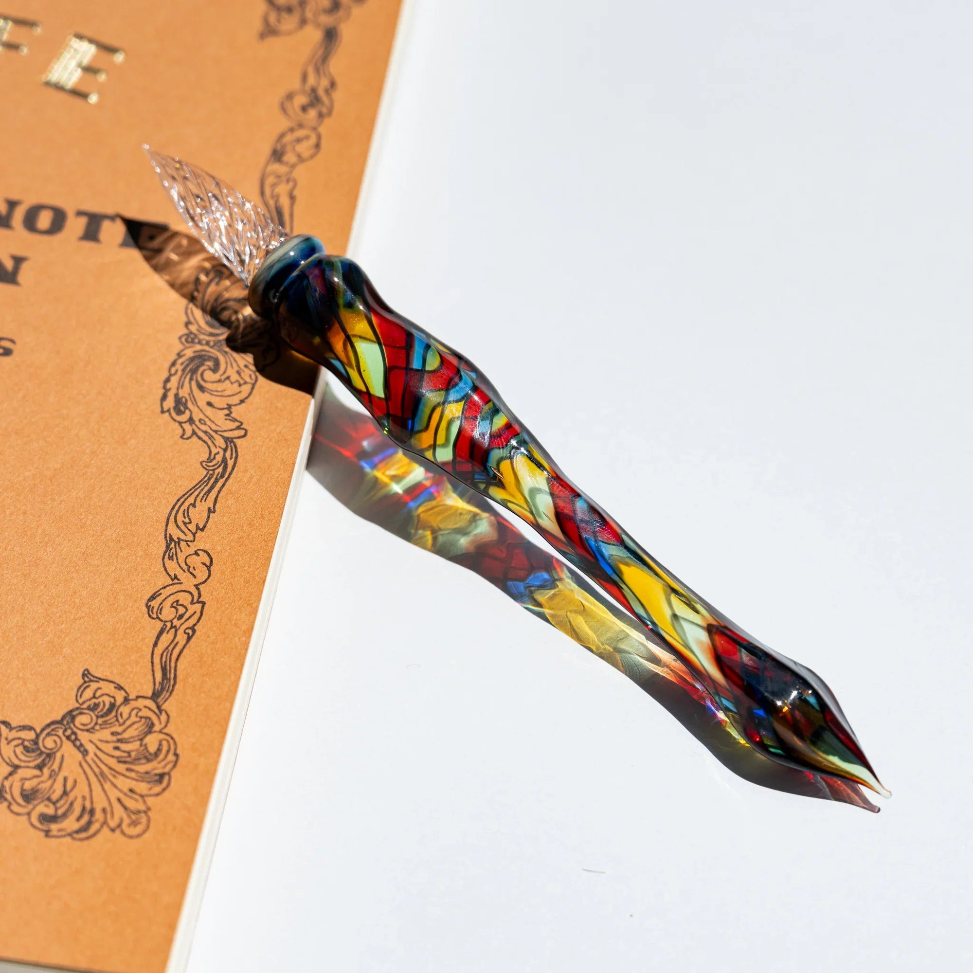 Cathedral glass dip pen with a clear twisted nib and a stained-glass mosaic body in red, yellow, blue and green